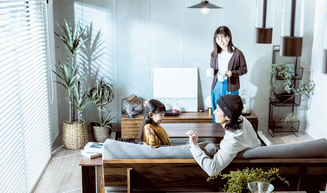 大きな窓に囲まれた明るいリビングで過ごす家族
